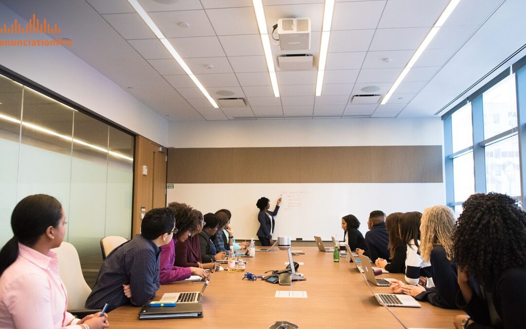 Diverse professionals seated along a long conference table while a presenter writes at a whiteboard