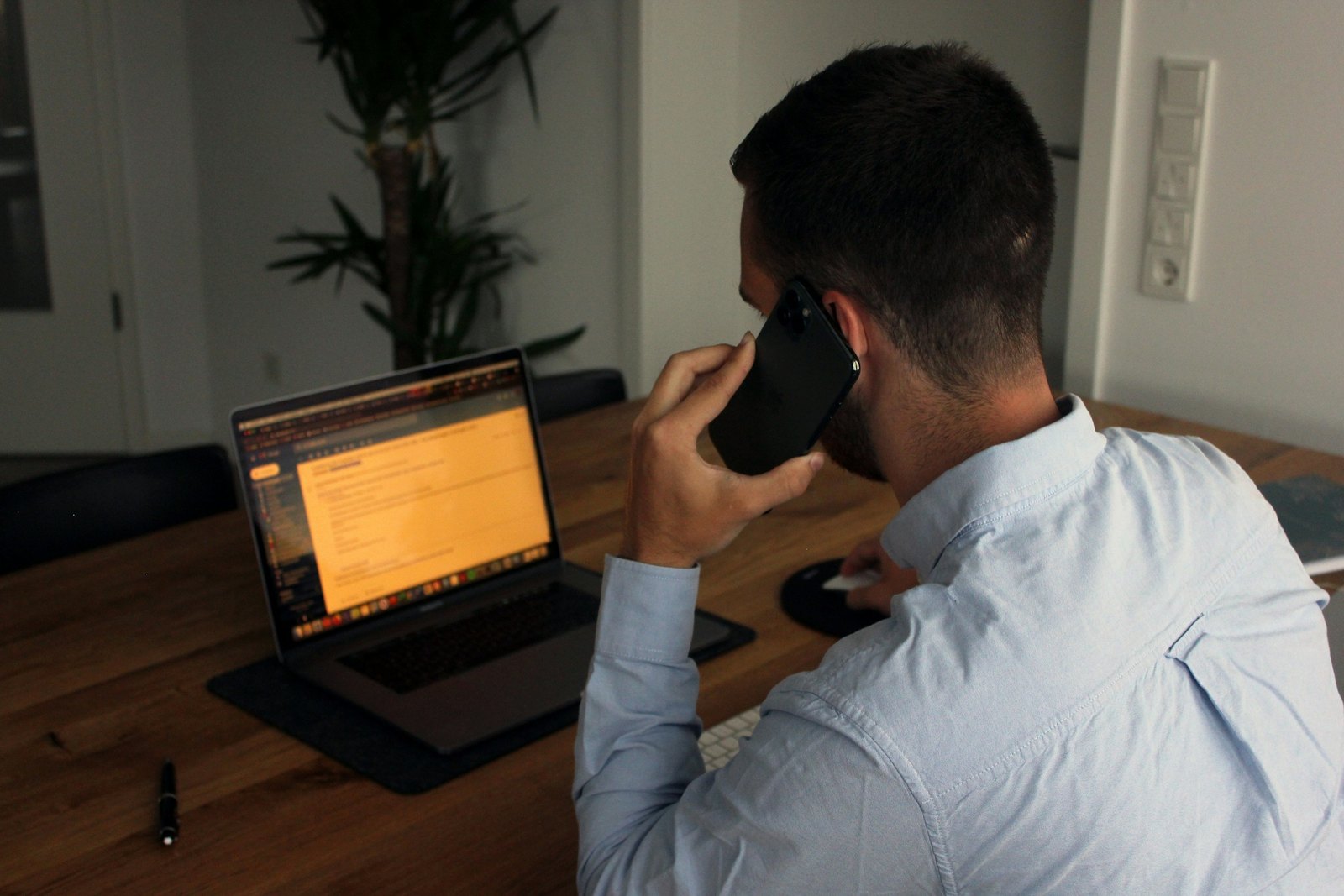 Man on a phone call while working at a laptop